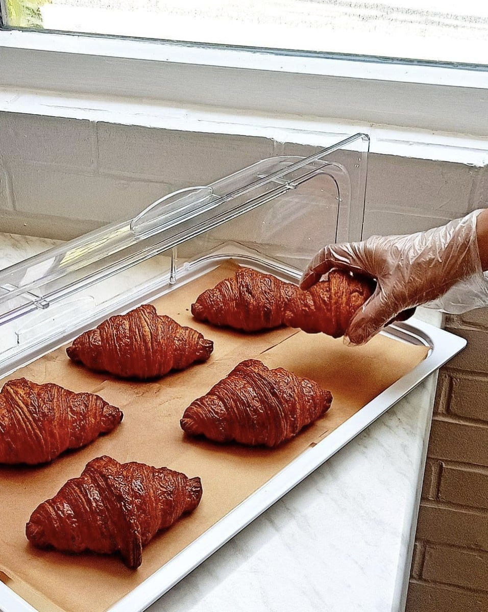 Freshly baked golden croissants on a tray at Sourdough Cafe